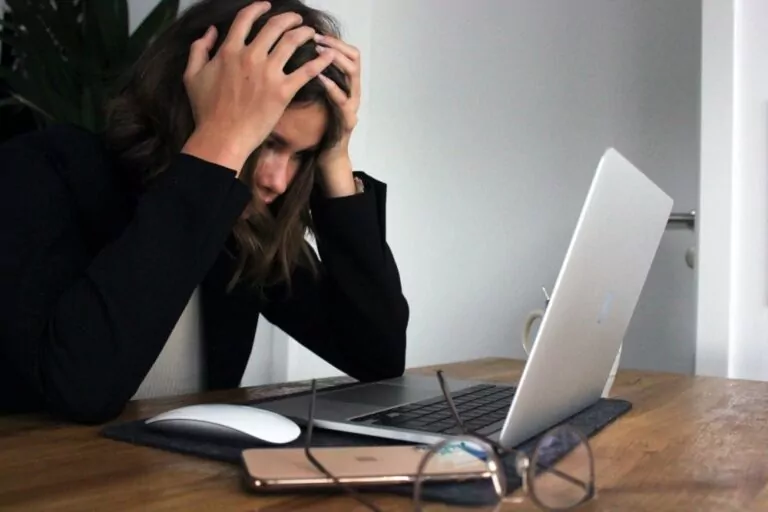 Woman in office setting stressed over her laptop by Elisa Ventur on Unsplash.