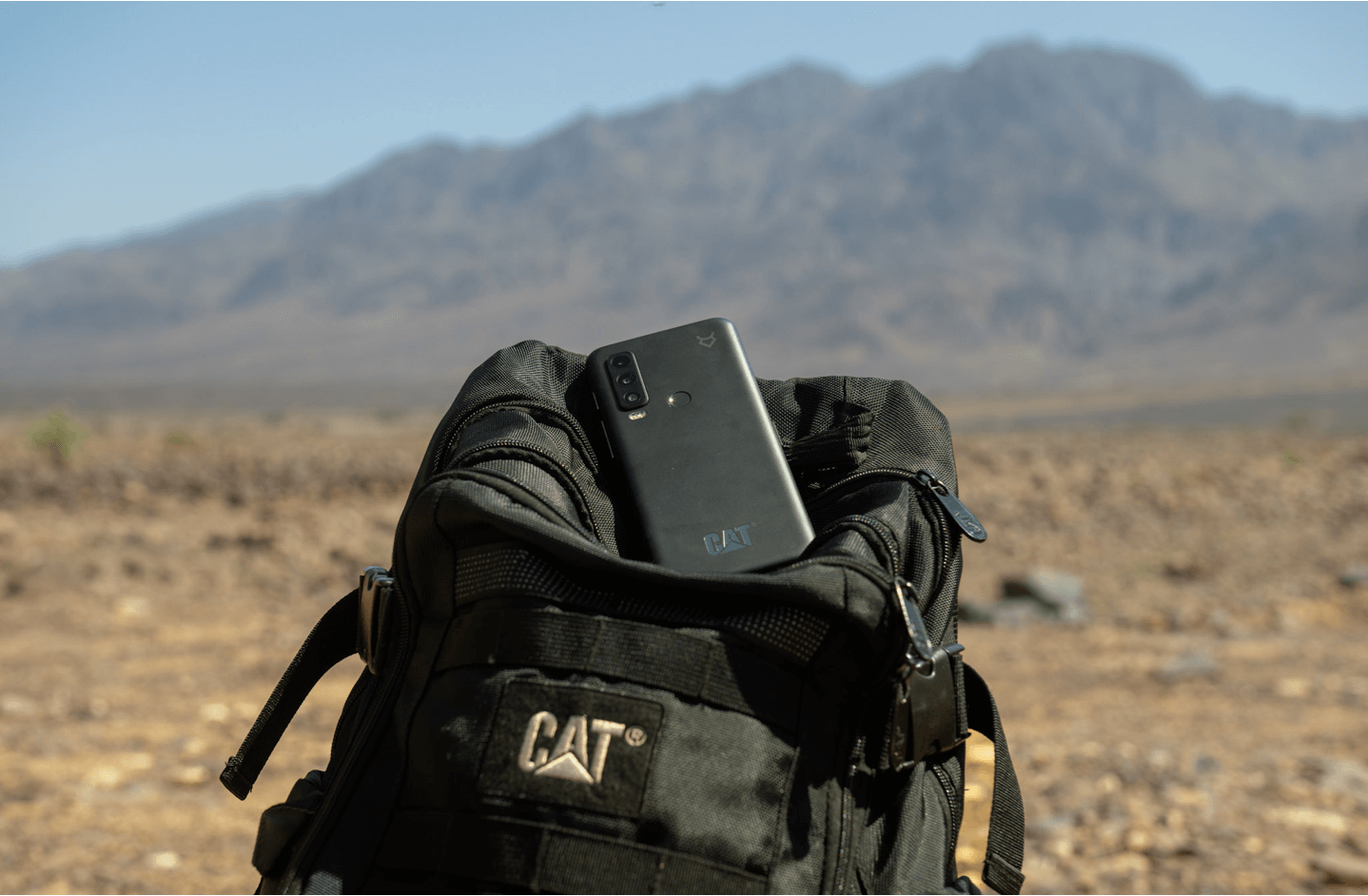 Cat S75 rugged phone placed on a black backpack in a desert landscape.