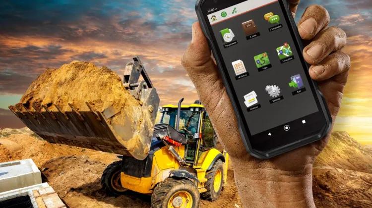 Kyocera DuraForce PRO 3 rugged phone held at a construction site with a loader in the background.