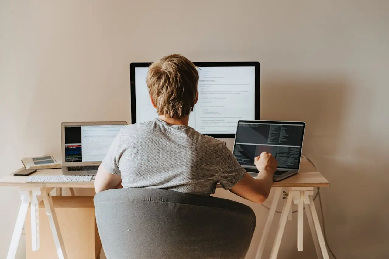 A guy working on two laptops and a desktop at the same time on his desk. Self hosted time tracking.