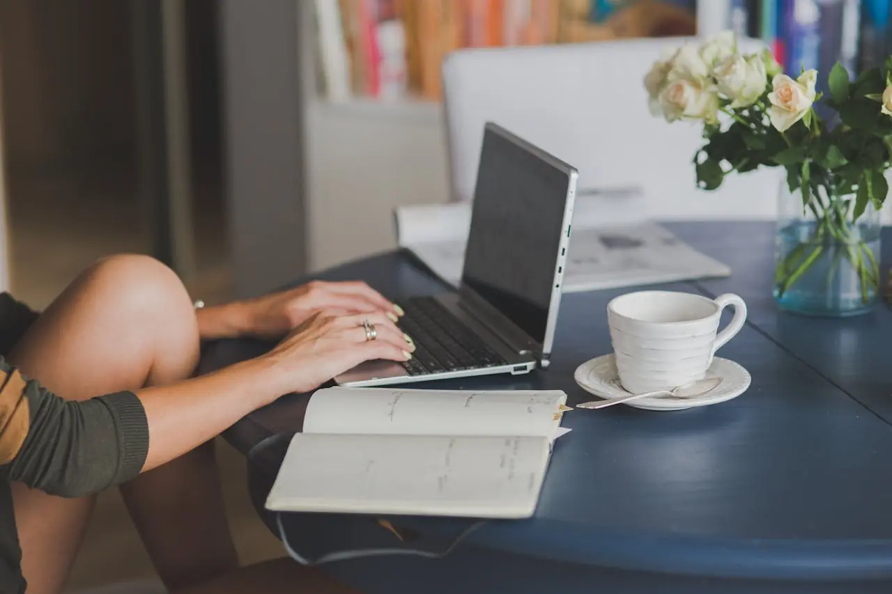 Alguém de uma empresa remota trabalhando em casa em seu notebook com uma xícara de café ao lado.