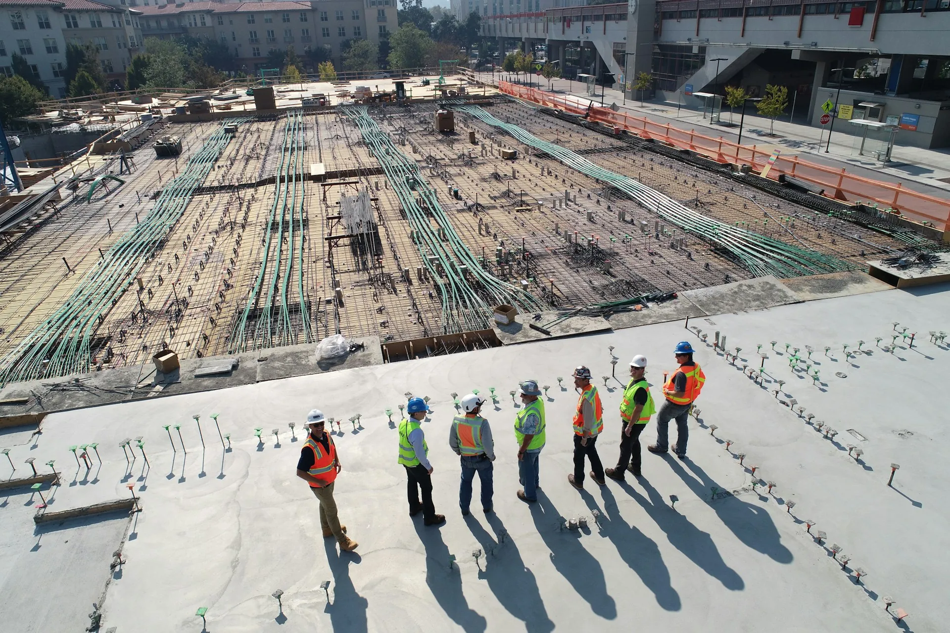 A construction team standing next to each other while looking over a construction site. Multi-site construction time tracking.