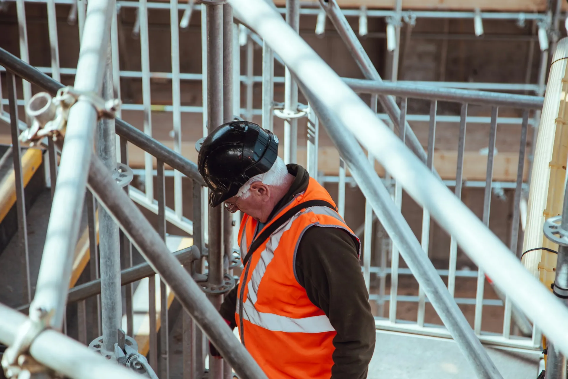 A construction worker wearing an orange vest at a construction site.