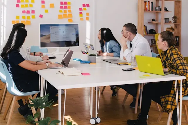 A group of employees having a meeting, looking at a presentation on the computer screen while at the office.