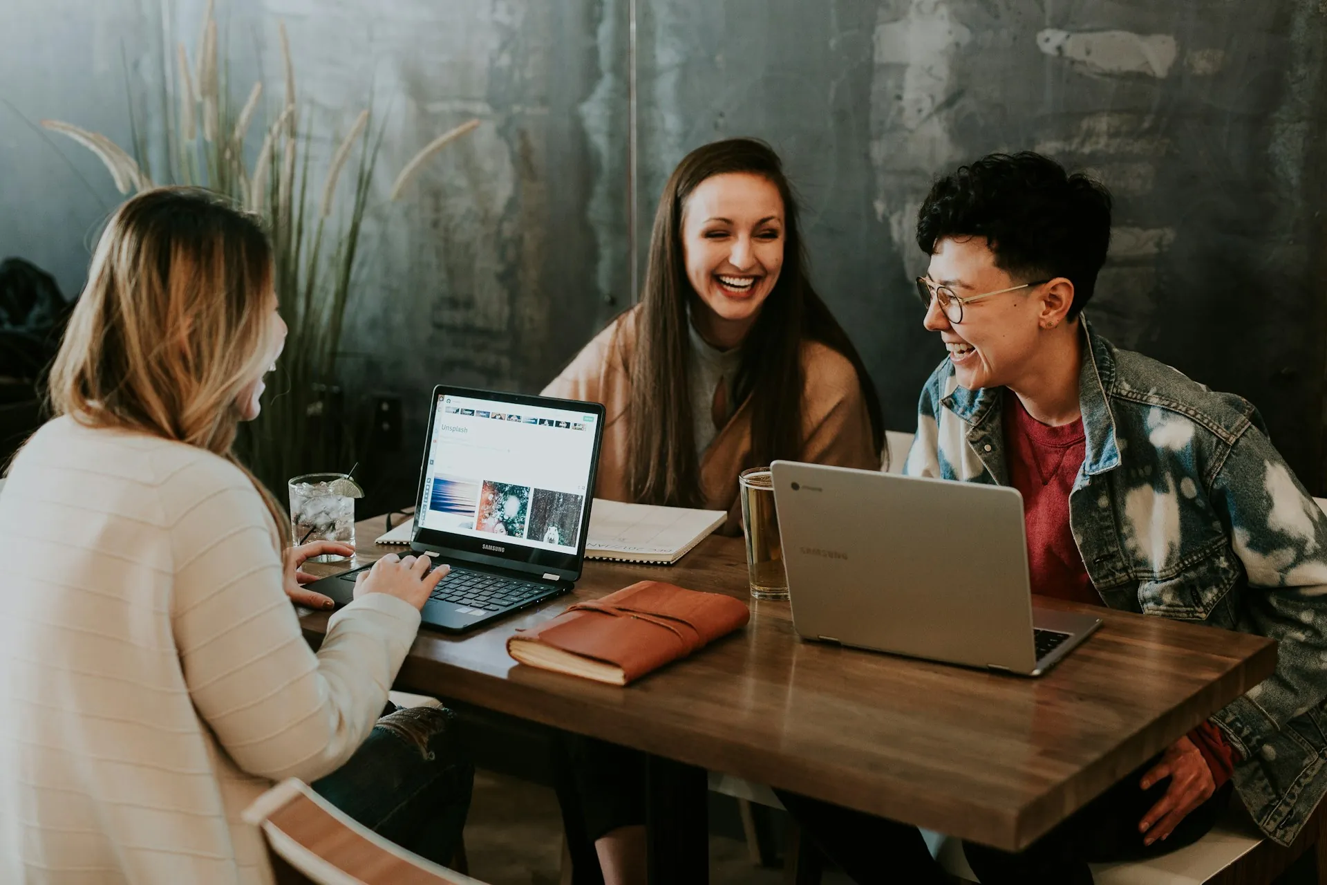 A group of employees talking and laughing while working on their laptops.