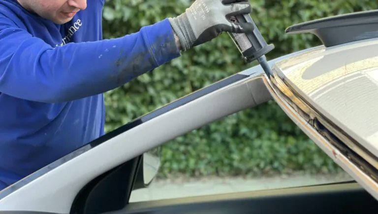 Man fixing windshield of car that has been fully removed