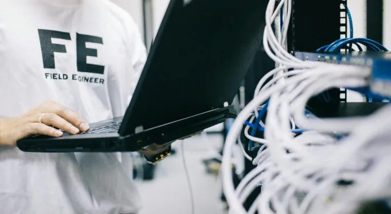 Field engineer examining hardware and working on laptop